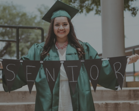educating our children, photo of a recent high school graduate hold a sign that says senior